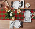 Table dressée avec des plats et des ustensiles sur un napperon à carreaux rouges, accompagnée d'un bouquet de fleurs blanches.
