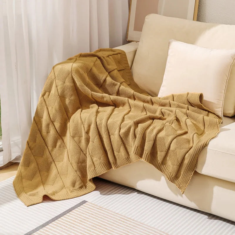 Une couverture tricotée jaune moutarde confortable et chaleureuse, apportant une touche d'automne cosy dans cette pièce de vie.