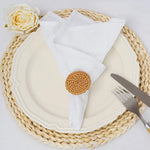 Une assiette blanche élégante repose sur un napperon en rotin, accompagnée d'une serviette de table blanche et d'une rose blanche.