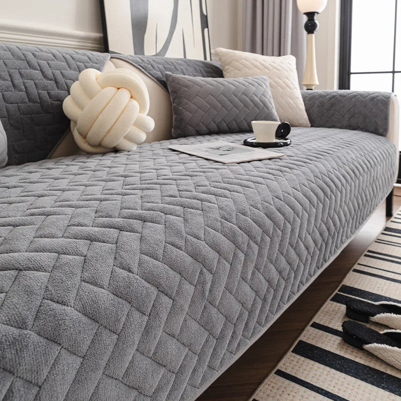 Cet espace de détente confortable présente un canapé gris matelassé avec de beaux coussins décoratifs, créant une atmosphère chaleureuse et apaisante.