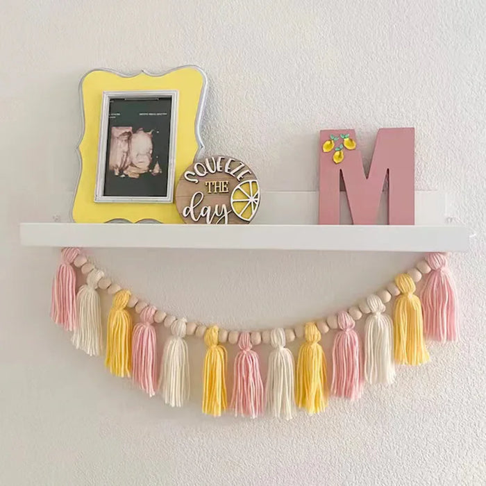 Guirlande de pompons roses avec perles en bois suspendue dans une chambre d'enfant