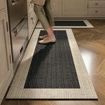Un tapis de cuisine moderne et élégant dans des tons neutres, avec un motif géométrique de lignes noires et grises, se marie parfaitement avec le sol en bois et les éléments de la cuisine.