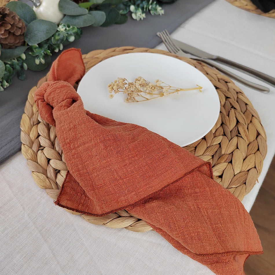 Une assiette blanche avec une broderie florale sur un napperon en fibres tressées, accompagné d'un linge de table orange.