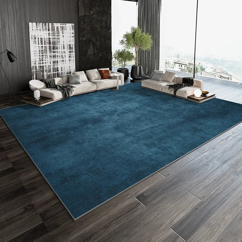 Un vaste salon moderne avec un grand tapis bleu foncé, des canapés confortables et une vue panoramique sur l'extérieur.