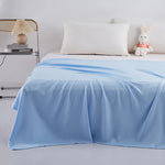Lit simple avec une couverture bleue pastel et des accessoires décoratifs, créant une atmosphère douce et relaxante dans la chambre.
