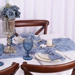 Une table de salle à manger élégante avec un centre de table floral composé de roses bleues et d'un bougeoir en argent, le tout sur un fond de rideaux blancs.