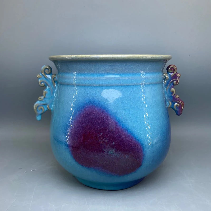 Pot en céramique bleu et violet avec des détails décoratifs sur les anses.