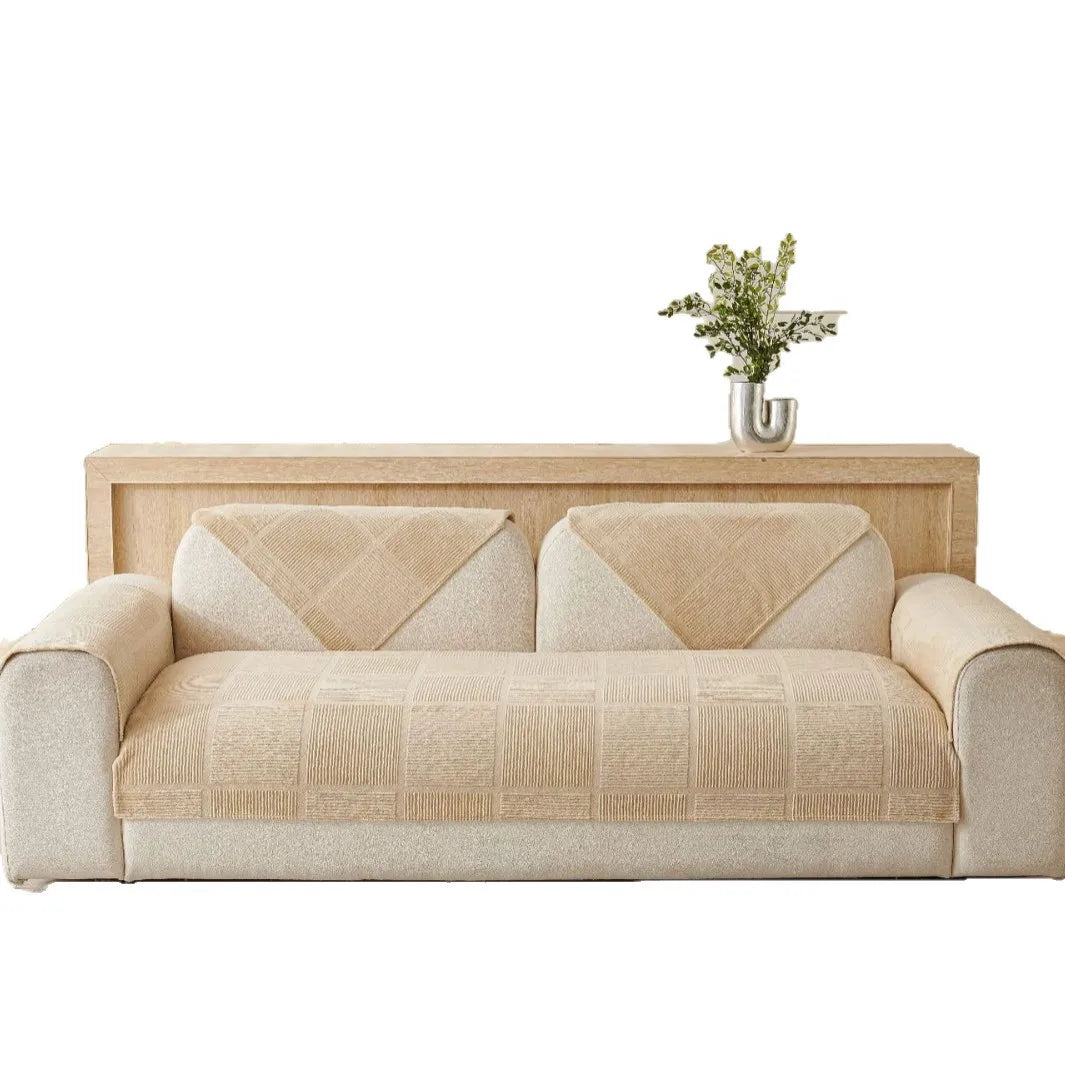 Un canapé en tissus beige avec des motifs géométriques et une table en bois clair surmontée d'un vase avec de la verdure.