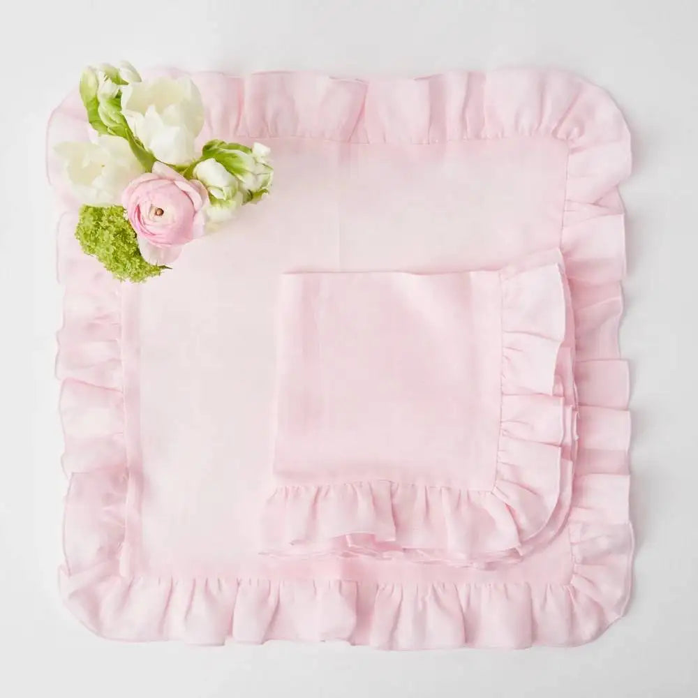 Délicate décoration florale sur une parure de lit en satin rose pastel, créant une ambiance élégante et raffinée.