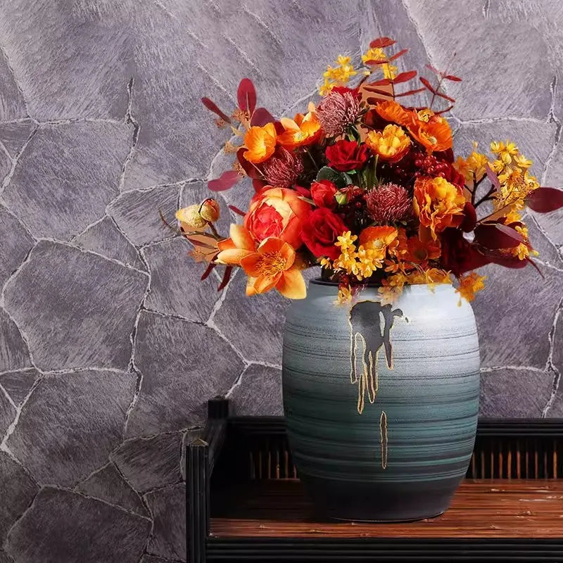 Un magnifique bouquet d'automne composé de fleurs vibrantes et de couleurs chatoyantes dans un vase aux nuances vertes et dorées, créant une atmosphère chaleureuse et harmonieuse.