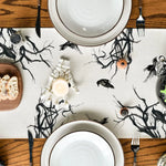 Composition sombre et mystérieuse avec des assiettes blanches, des bougies, et des ornements noirs rappelant une ambiance d'Halloween.