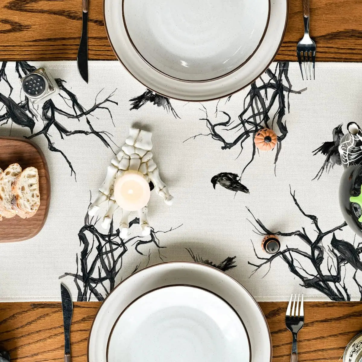 Composition sombre et mystérieuse avec des assiettes blanches, des bougies, et des ornements noirs rappelant une ambiance d'Halloween.