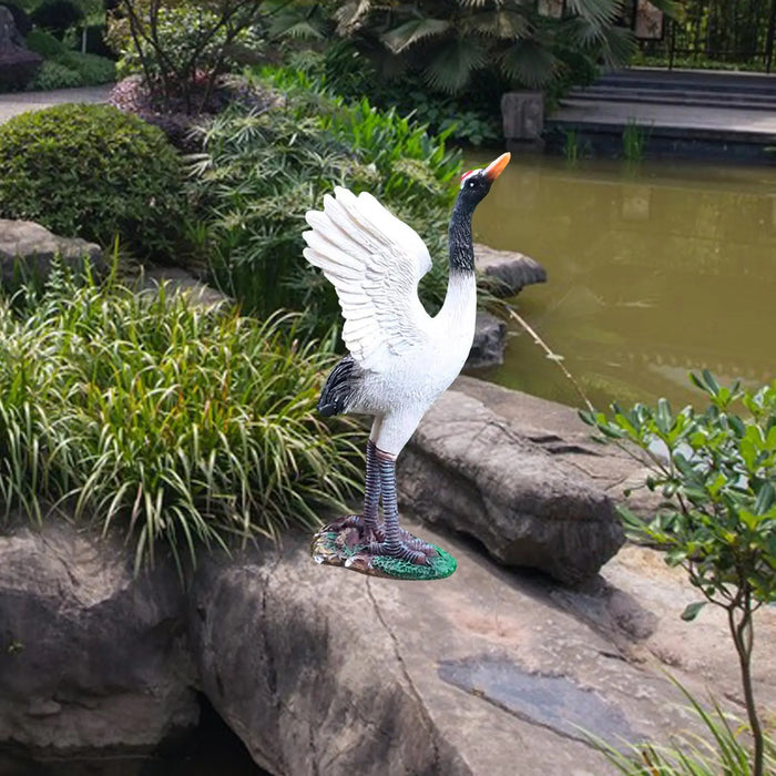 Statue de grue en résine grise dans un jardin