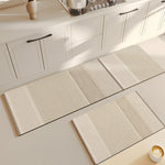 Motifs de tapis et de passants de porte en fibres naturelles sur un sol de cuisine blanc.