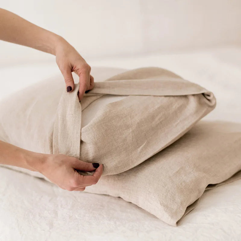 Une main délicate ajuste un linge de lit beige, évoquant le confort et la tranquillité d'un bel intérieur.
