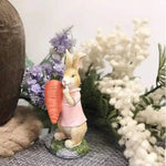 Une délicate figurine de lapin en porcelaine tenant une carotte, entourée de belles fleurs.