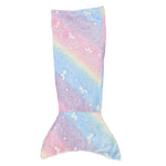 Une queue de sirène en peluche douce et colorée, avec des motifs de licornes et d'étoiles sur un arrière-plan arc-en-ciel.