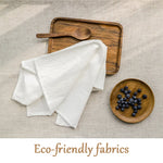 Produits de cuisine écologiques avec nappe blanche, planche à découper en bois et bol en bois rempli de baies bleu foncé.