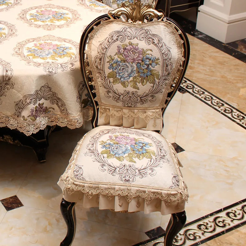 Chaise rembourrée ornée de broderies florales aux teintes pastel, avec un dossier sculpté et encadré de motifs décoratifs sur fond clair.