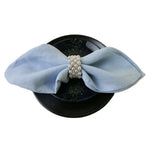 Casquette noire avec un ruban bleu pâle et un bouton de perles décoratif en son centre.