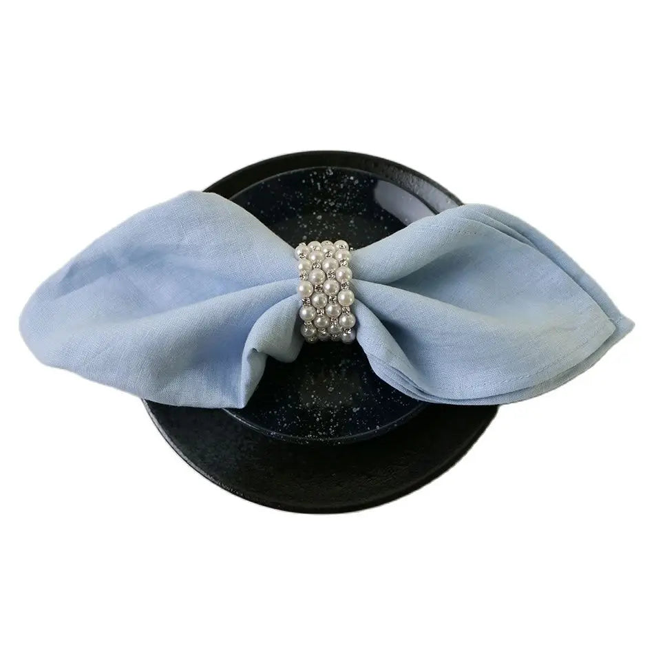 Casquette noire avec un ruban bleu pâle et un bouton de perles décoratif en son centre.