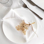 Le centre de l'assiette blanche est décoré d'un bouquet de fleurs séchées, créant une présentation délicate et naturelle pour un repas raffiné.