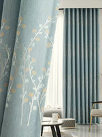 Des rideaux de design d'intérieur en textile bleu luxueux avec un motif floral, suspendus comme une solution de traitement de fenêtre dans un salon bien aménagé. La pièce contient également des éléments de décoration comme une lampe moderne, un pot de fleurs avec une belle plante d'intérieur sur un papier peint élégant. Une idée parfaite de revêtement de fenêtre pour améliorer l'esthétique de votre espace de vie.