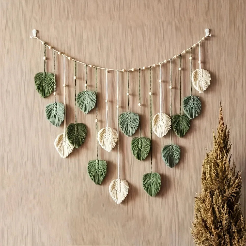 Macramé plume abricot accroché au mur près d'une plante