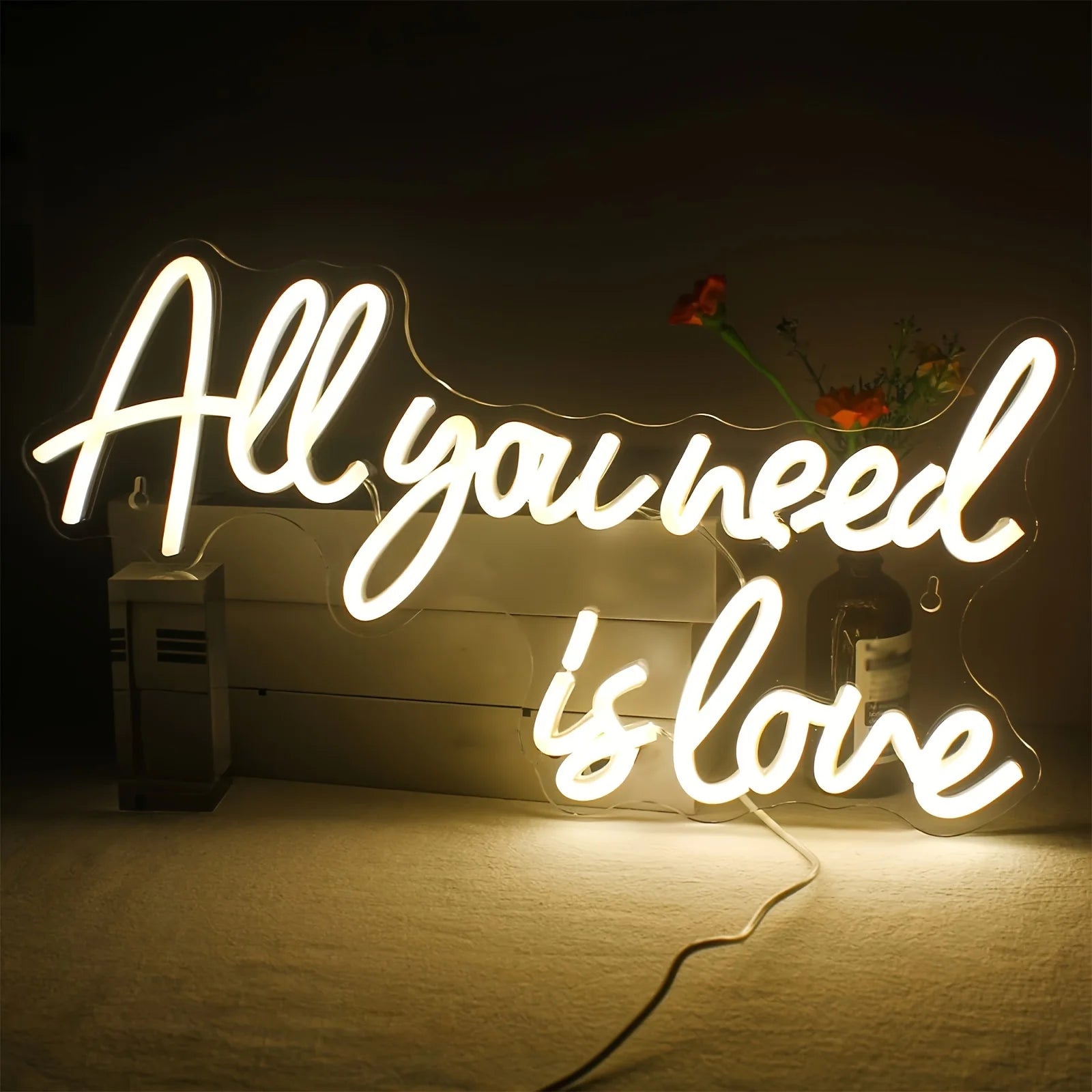 Enseigne au néon LED 'Tout ce dont vous avez besoin est amour' allumée dans une chambre