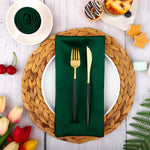 Une table de décoration élégante avec une assiette, des couverts dorés sur une serviette verte, entourée de fleurs et de gâteaux.