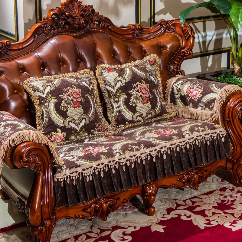 Canapé en bois taillé finement avec des ornements baroque en relief, recouvert de coussins tissu aux motifs floraux et d'un plaid frangé, créant une atmosphère luxueuse et élégante.