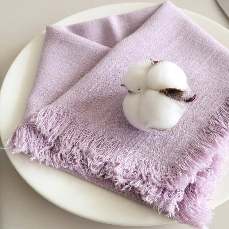 Une fleur de coton posée sur une serviette texturée de couleur lavande, créant une composition élégante et naturelle.