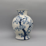 Vase décoratif en porcelaine blanche et bleue avec motif de fleurs de cerisier en fleurs.