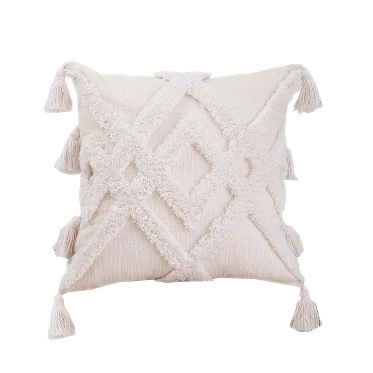 Coussin décoratif en tissu éponge blanc avec motifs géométriques et franges.