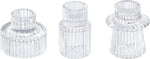 Trois photophores en cristal transparent aux formes distinctives, disposés sur un fond blanc, constituant un ensemble décoratif élégant et raffiné.