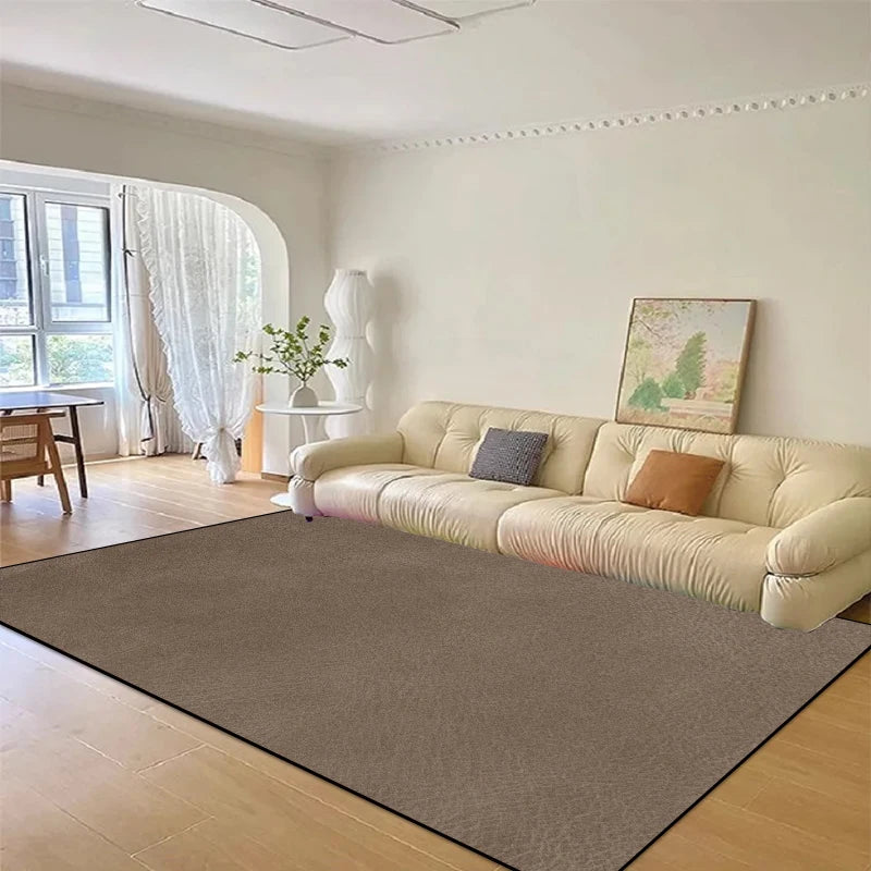 Élégant salon avec canapé beige, table et rideaux blancs, et tableaux muraux dans un intérieur lumineux et spacieux.