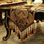 Un magnifique chemin de table en velours richement décoré de motifs floraux et ornements dorés, créant une ambiance élégante et chaleureuse pour une table de fête.