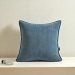 Coussin décoratif gris foncé en texture de chevrons sur une étagère blanche avec accessoires.