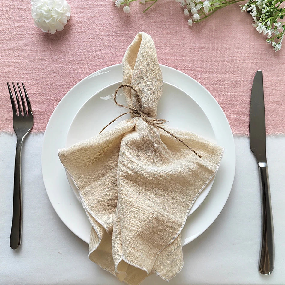 Une décoration élégante pour une table dressée avec soin, mettant en valeur un pli de tissu beige enroulé autour d'une assiette blanche, accompagné d'une fourchette et d'un couteau.