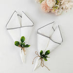 Serviettes de table blanches décorées de feuilles de verdure, liées avec de la ficelle de jute, entourées d'un bouquet de fleurs roses délicates sur fond blanc.