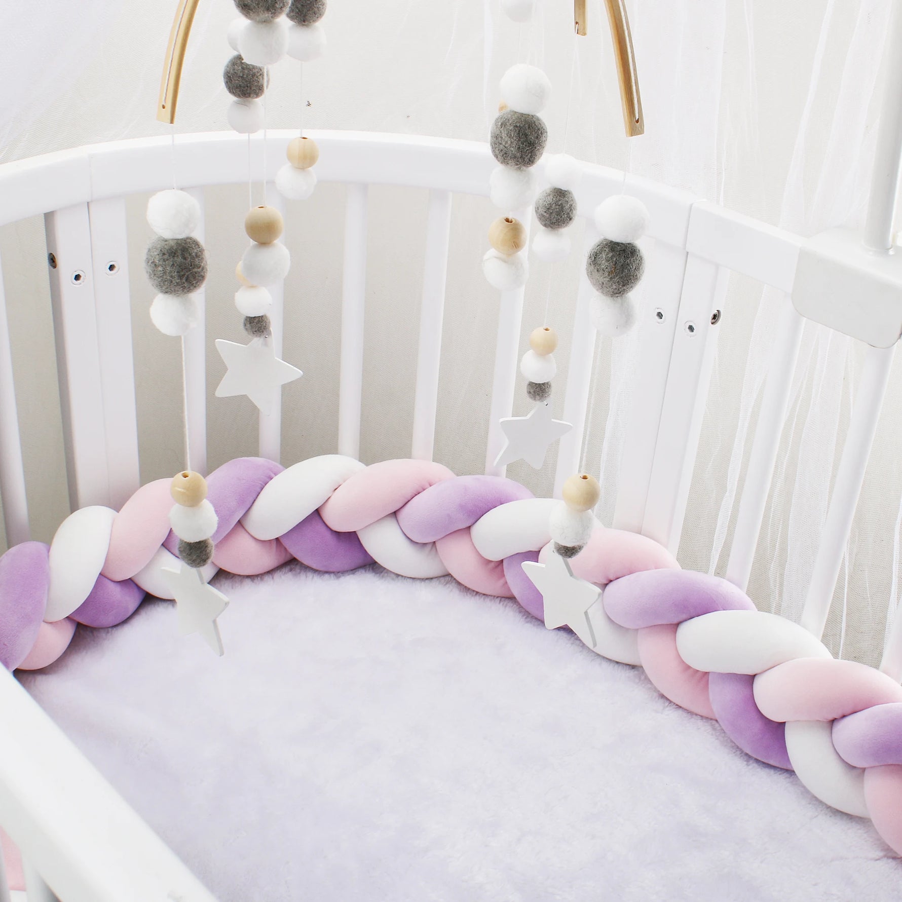 Pare-chocs de lit bébé installé dans un berceau avec décoration coordonnée