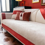 Un canapé moelleux avec des coussins décoratifs rouges et beiges, dans un salon élégant avec des détails dorés et des rideaux verts.