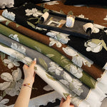 Une image d'un espace de travail créatif avec des matériaux textiles floraux et un ordinateur portable sur un plateau en bois.