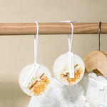 Deux petits disques blancs suspendus à une tringle, avec des morceaux d'écorce et de bois à l'intérieur, donnant un aspect naturel et rustique.