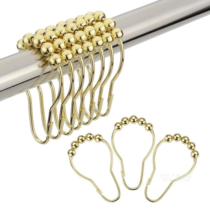 Crochets dorés pour rideaux suspendus sur une tringle métallique, avec perles coulissantes pour une ouverture fluide.