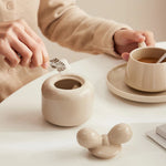 Une tasse de café et une théière en céramique blanche posées sur une table.