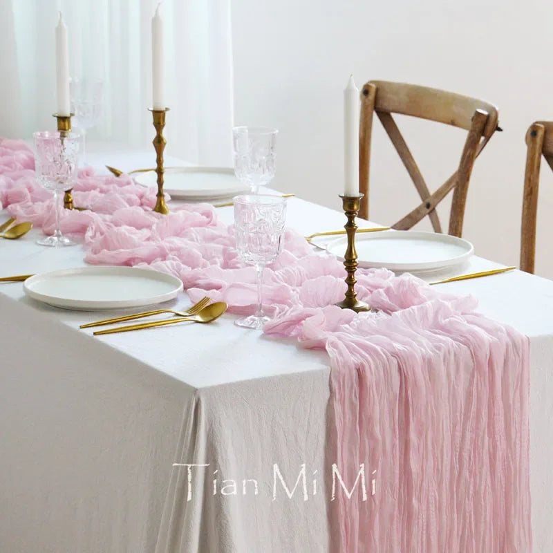 Une table élégante avec des décorations roses et dorées, incluant des bougies, une nappe en dentelle et des verres de cristal.