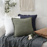 Coussins décoratifs dans des tons de gris et de vert, placés sur un lit avec une couverture texturée, créant une ambiance chaleureuse et apaisante dans la chambre.