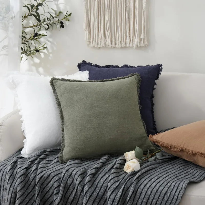 Coussins décoratifs dans des tons de gris et de vert, placés sur un lit avec une couverture texturée, créant une ambiance chaleureuse et apaisante dans la chambre.