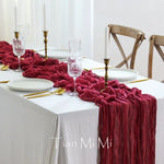 Une table élégante drapée de rouge, avec des chandeliers, des verres et des couverts dorés, créant une ambiance chaleureuse et raffinée.